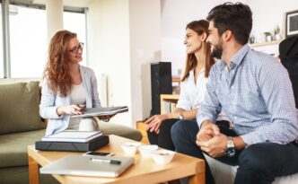 Real estate agent discussing strategy with a couple in a living room.