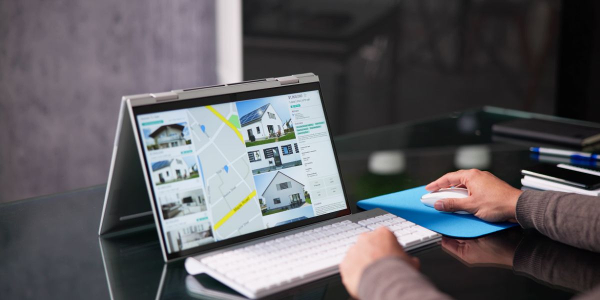 Person using a laptop displaying real estate listings with a map and property photos