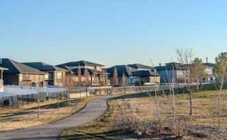 Bright, sunny street view of modern single-family homes in a residential Denver, Colorado neighborhood, representing the l...