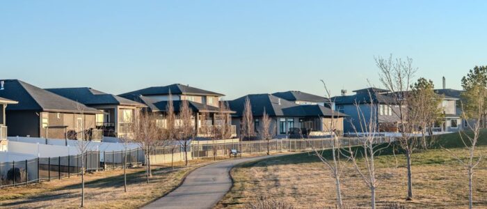 Bright, sunny street view of modern single-family homes in a residential Denver, Colorado neighborhood, representing the l...