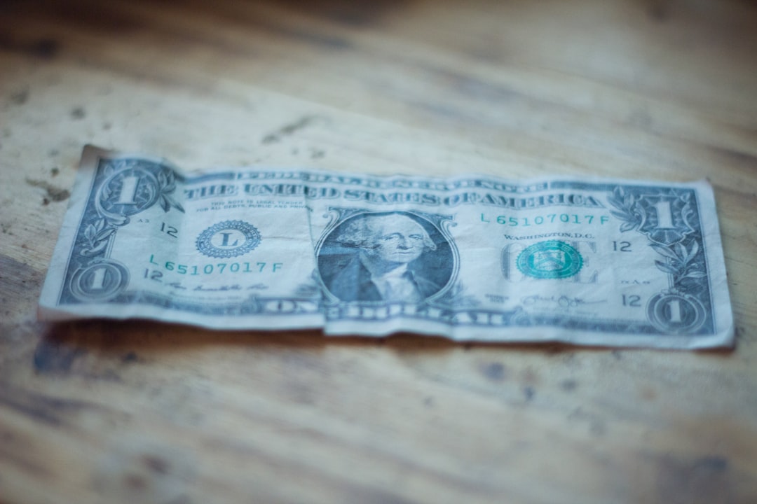 A minimalist photo of a single house key next to a one-dollar bill on a clean, white surface, symbolizing real estate commission savings.
